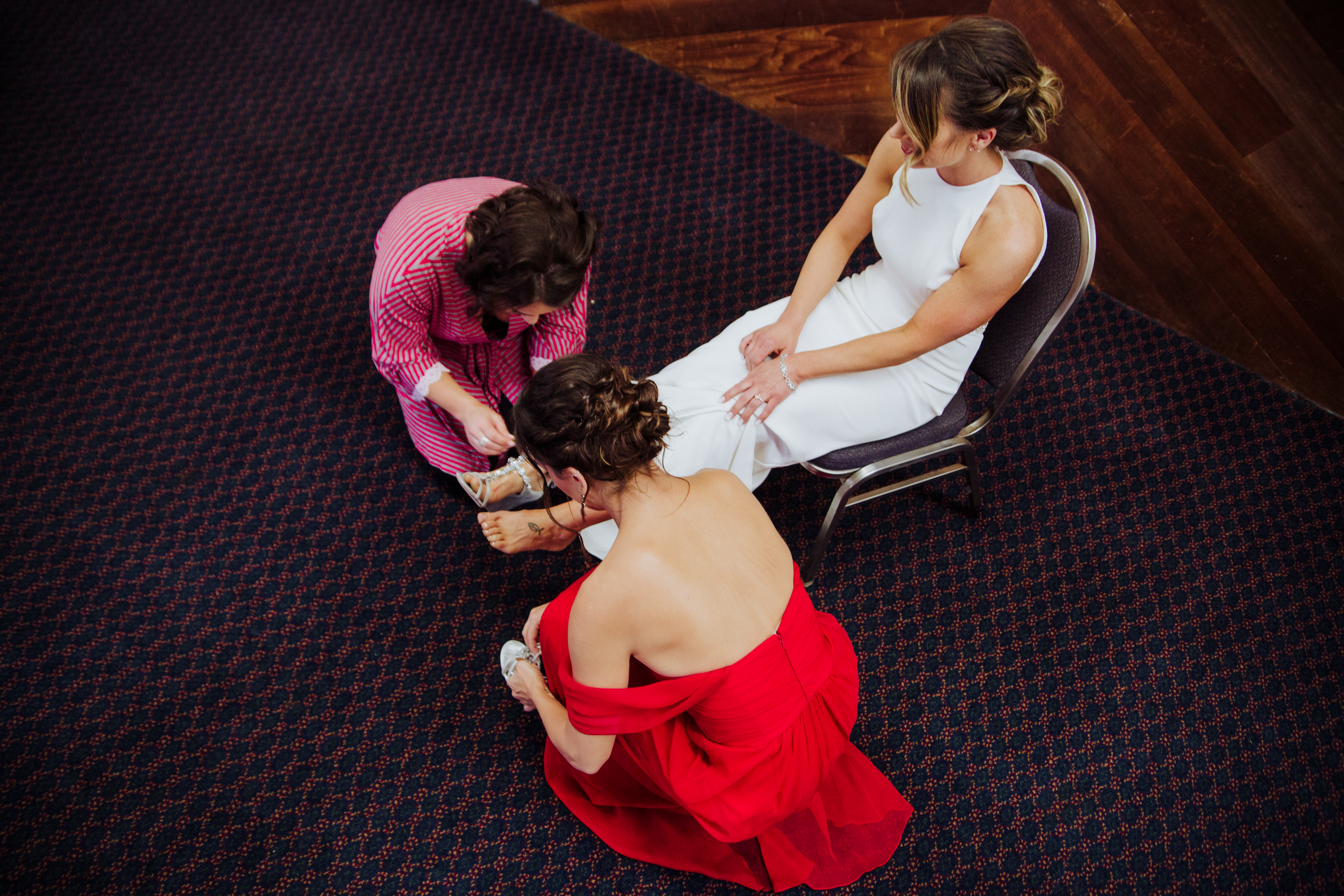Bridesmaids putting on Brides shoesat a Romantic Style San Diego Wedding at Marina Village by Kylie Rae Photography
