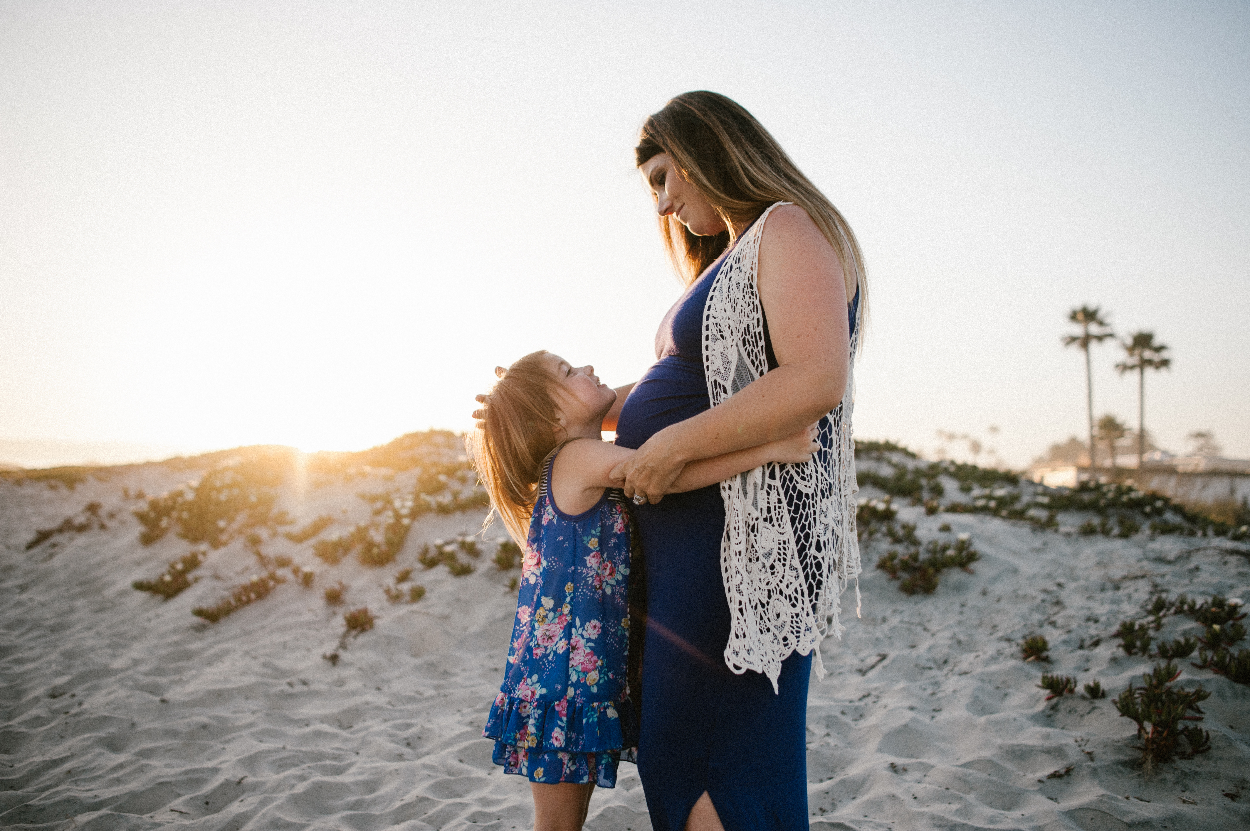 Sister kissing bellyfamily session at Coronado Beach by Kylie Rae Photography